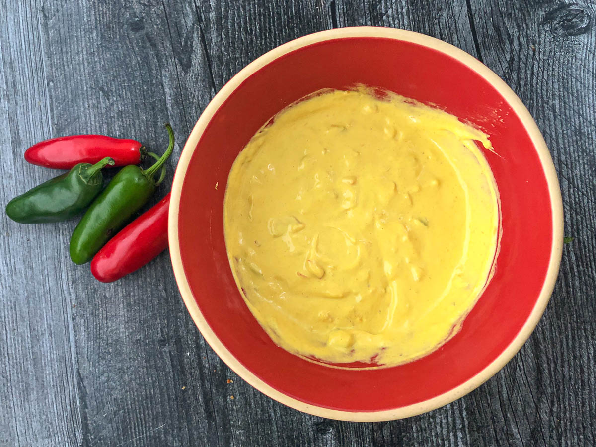 red bowl with finished mustard alongside fresh jalapeno and Serrano peppers