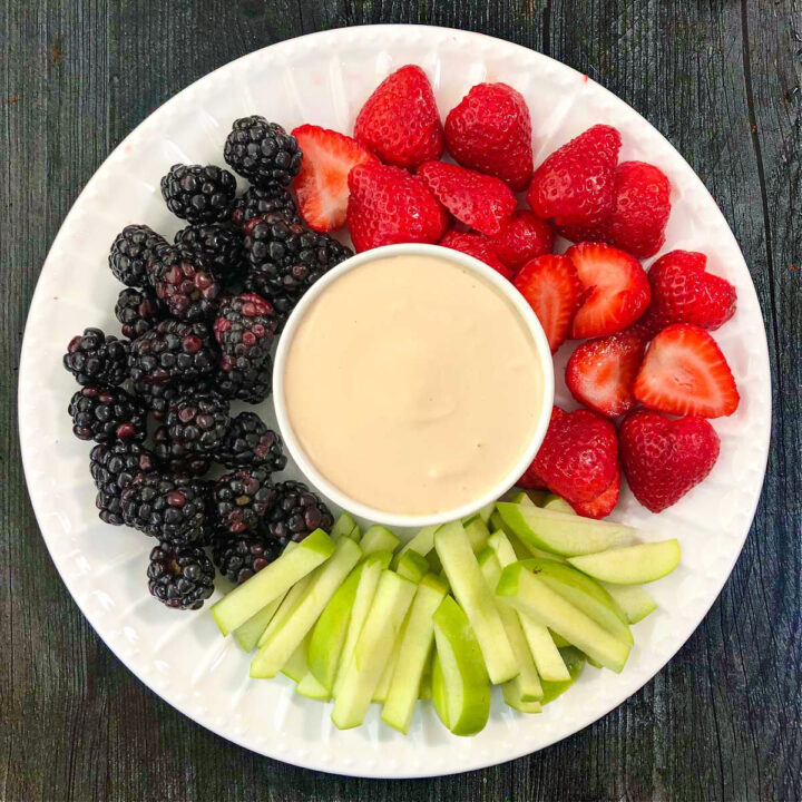 white plate with maple keto fruit dip and fresh fruit surrounding