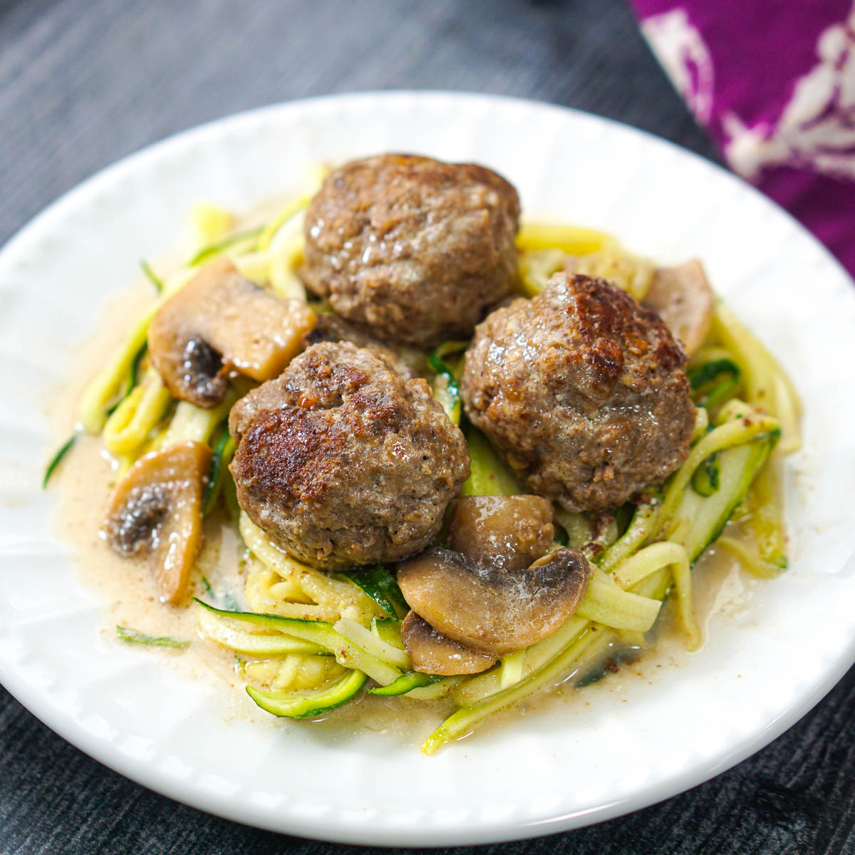 white plate with zucchini noodles topped with keto meatball stroganoff