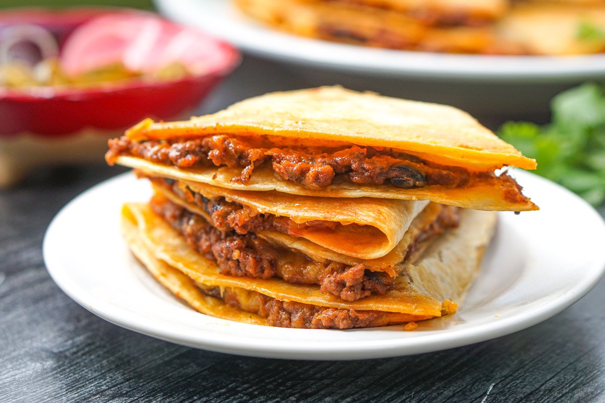 closeup of a stack of chili quesadillas on white plate