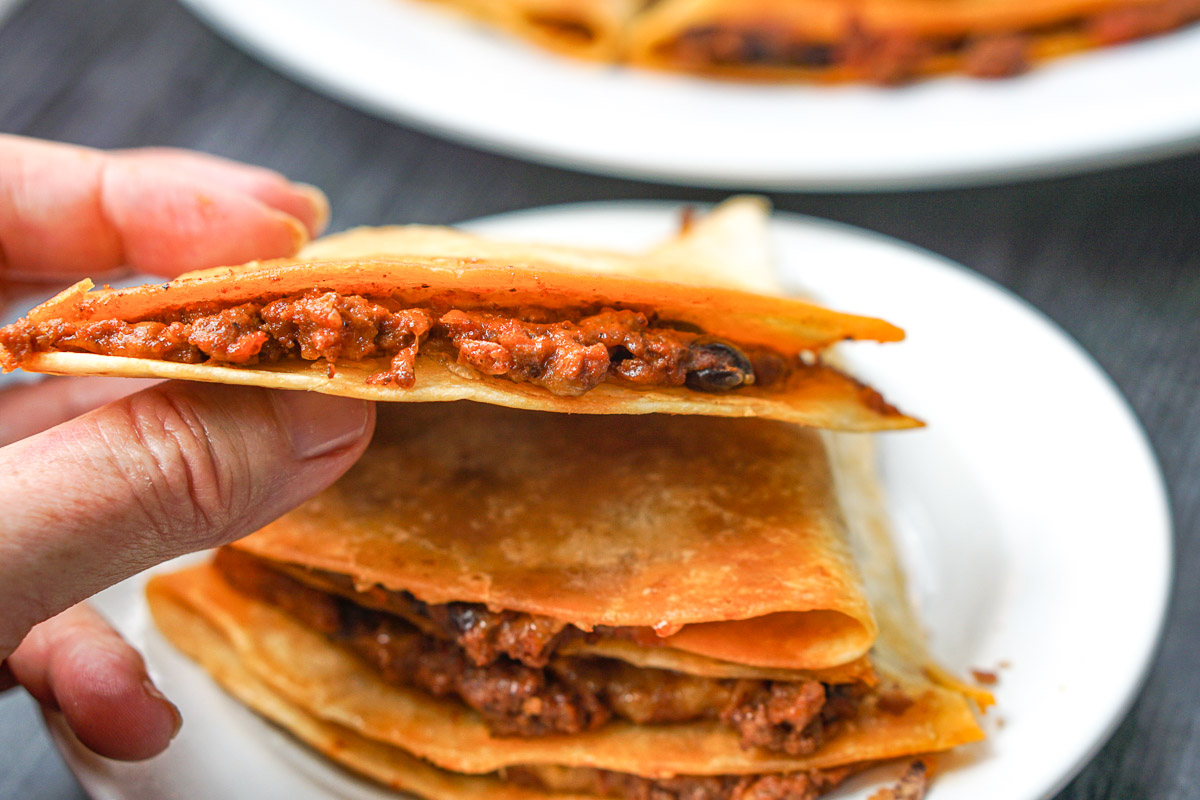 fingers holding a finished chili quesadillas