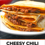 closeup of a stack of chili quesadillas on white plate with text