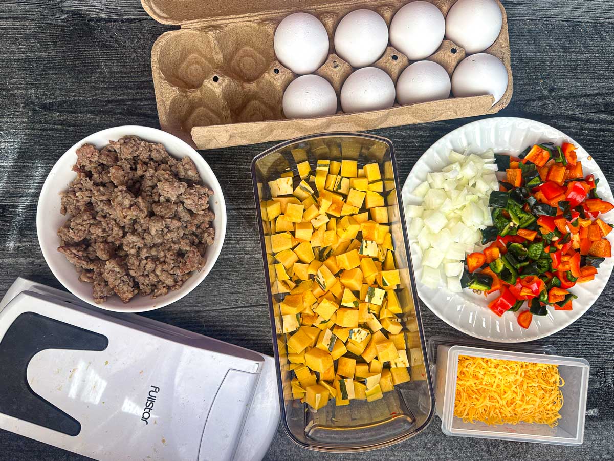 Recipe ingredients - eggs, breakfast sausage, delicata squash, onions, peppers and cheese.
