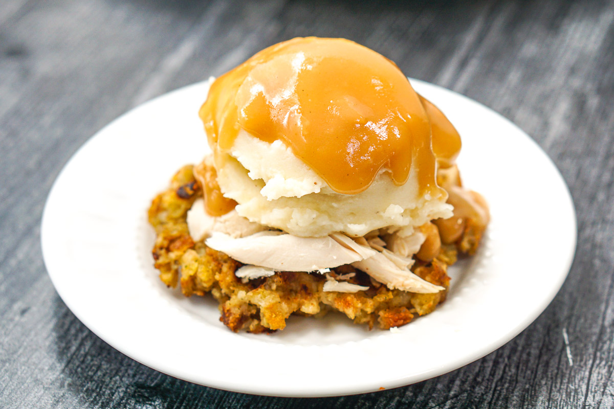 closeup of white plate with stuffing waffle topped with Thanksgiving turkey, mashed potatoes and gravy