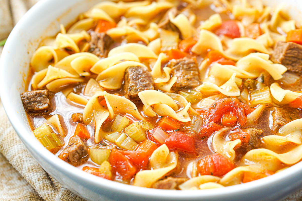 closeup of big white bowl with beef noodle and vegetable soup