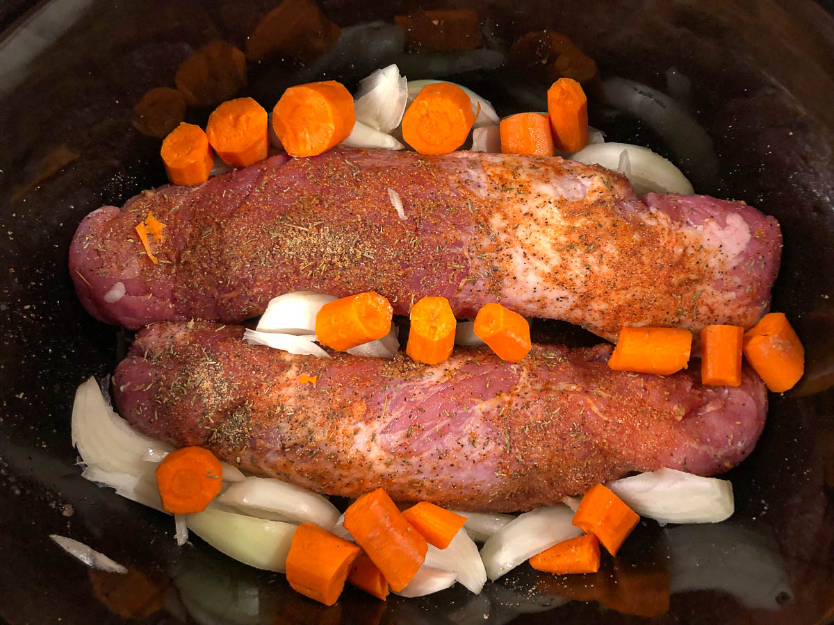 crockpot with raw pork and vegetables