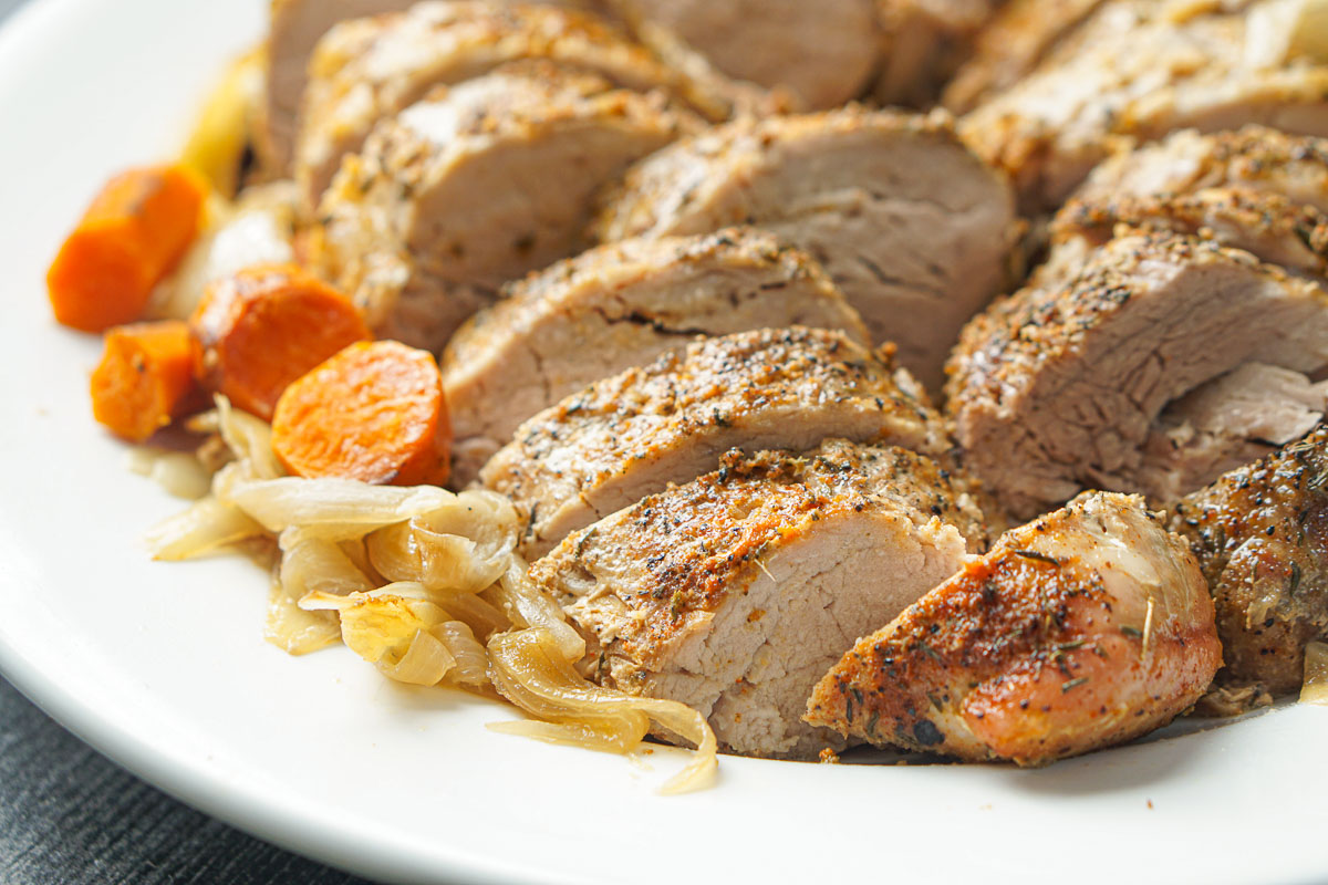 closeup of slice pork roast with carrots and onions
