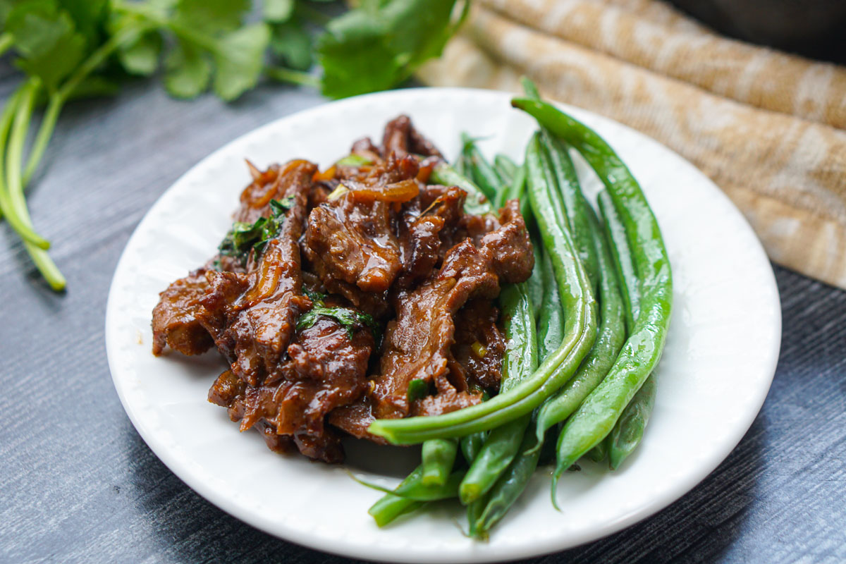 white plate with green beans and asian beef stir fry