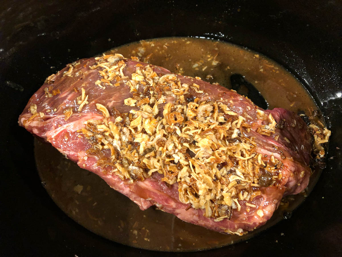 crock pot with raw chuck roast with onion soup mix on top