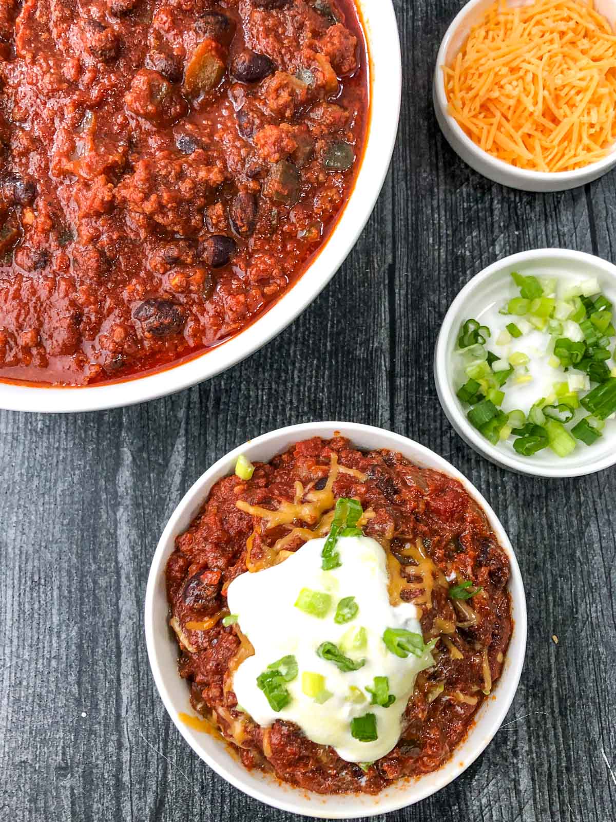 aerial view of white bowls with slow cooker chili and toppings