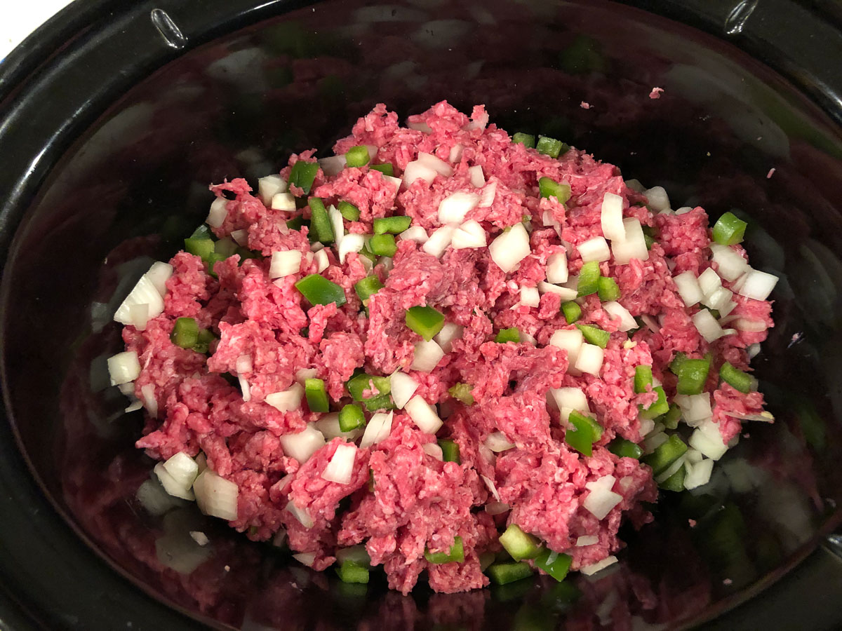 crockpot with raw ground beef, onions and peppers