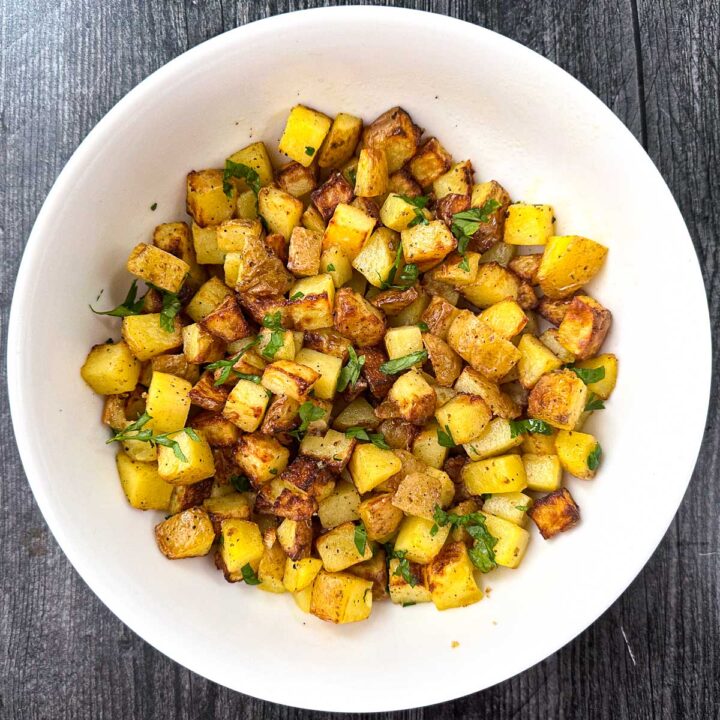 white bowl with air fryer diced potatoes and parsley