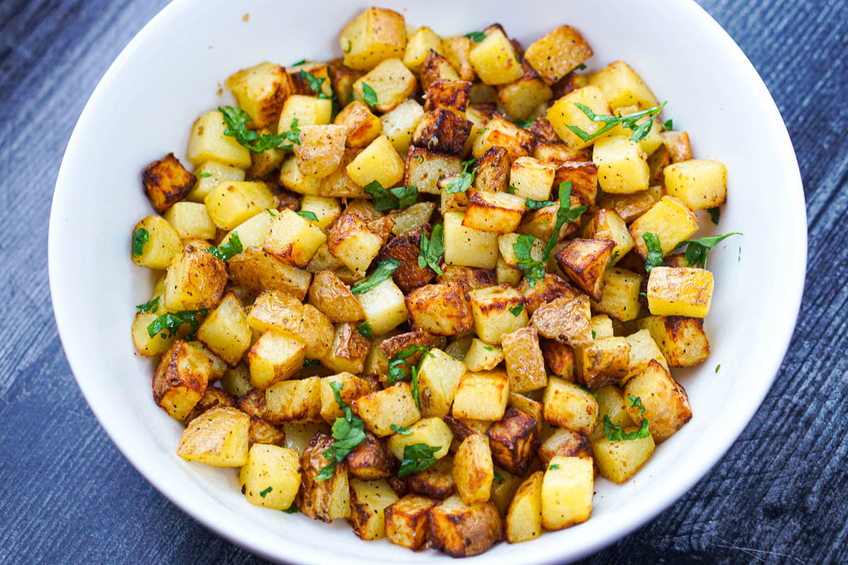 white bowl with air fryer diced potatoes and parsley
