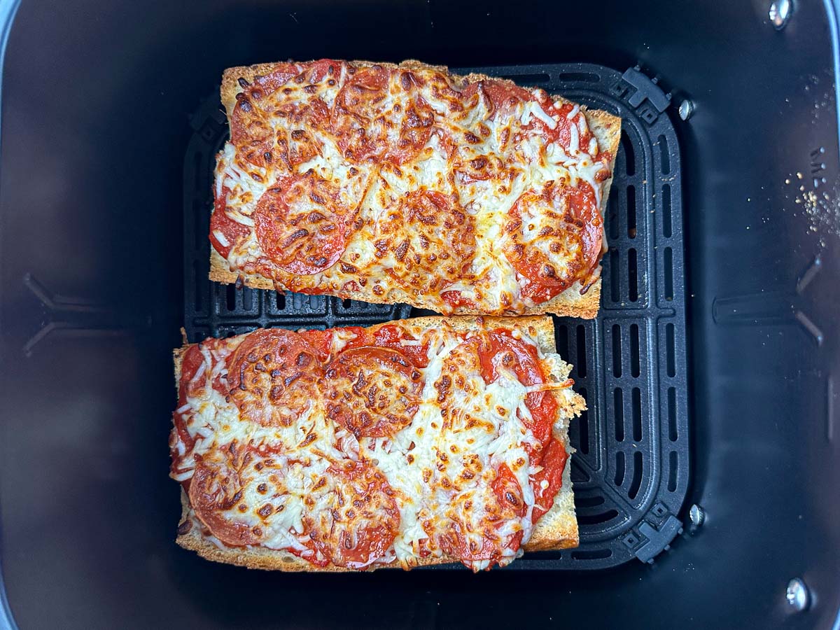 air fryer basket with 2 finished French bread pizzas