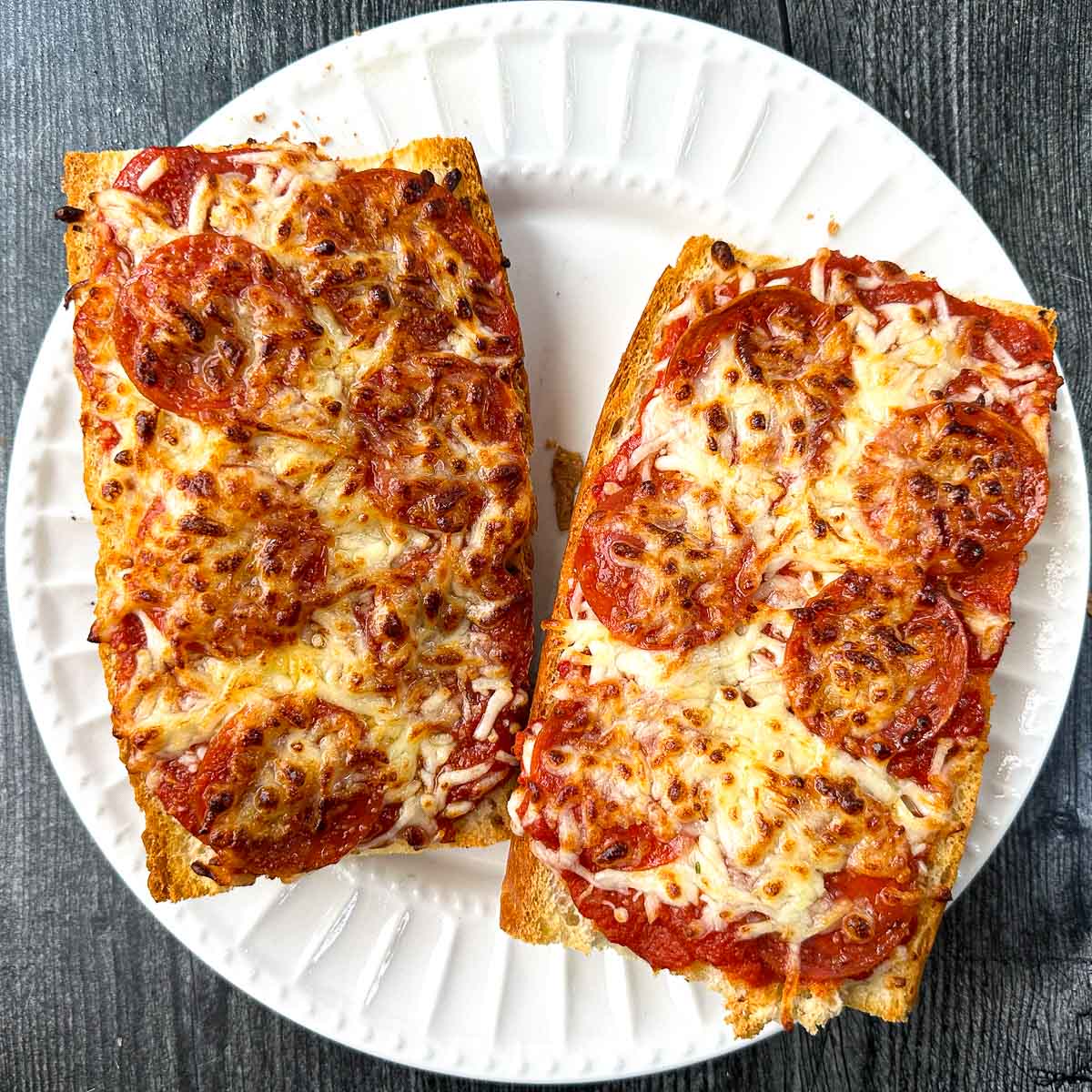 white plate with 2 French bread pepperoni pizzas