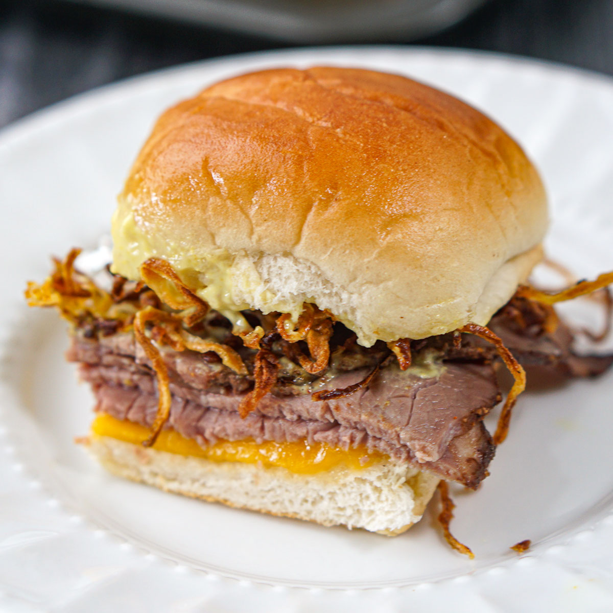 closeup of a roast beef slider on white plate