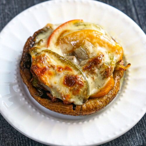 White plate with Philly cheesesteak stuffed portobello mushrooms.