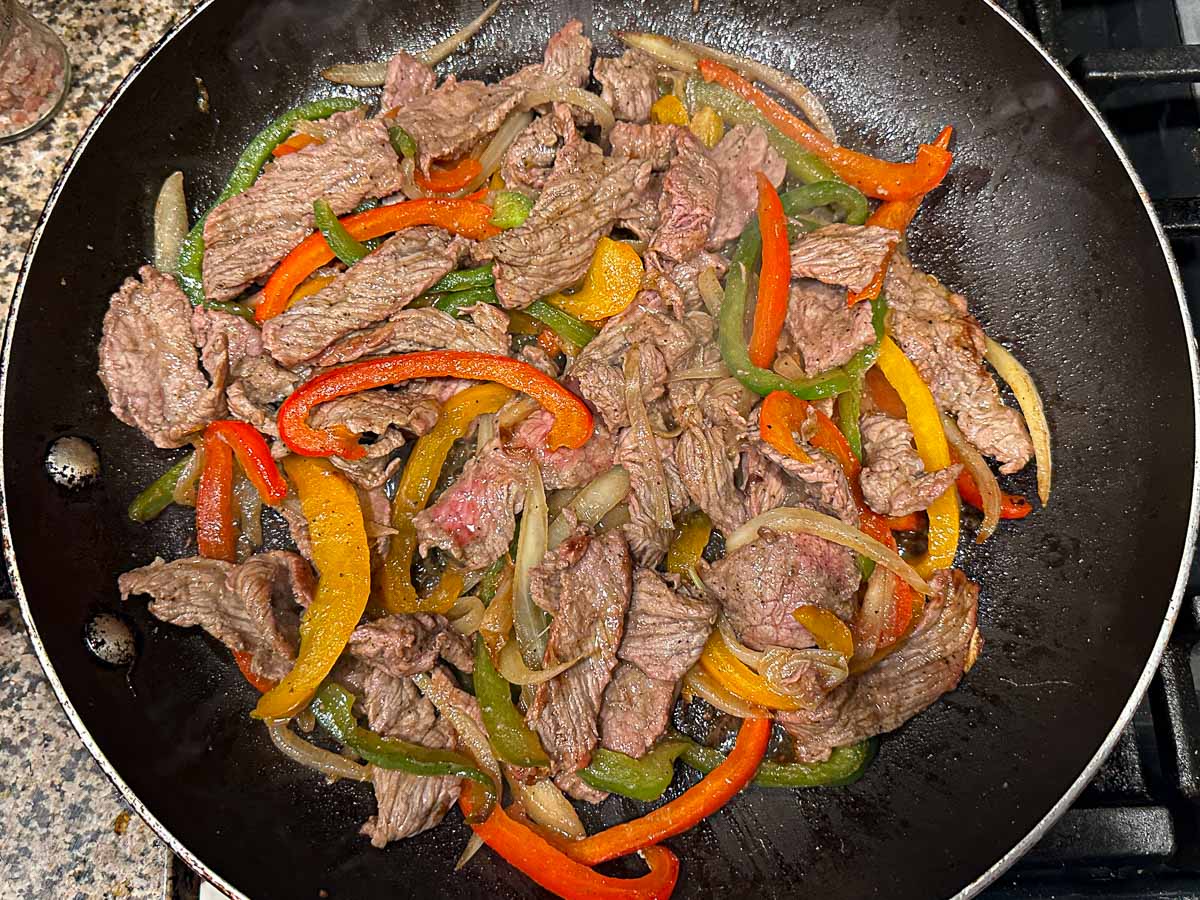 Skillet with sautéed steak, onions and peppers.