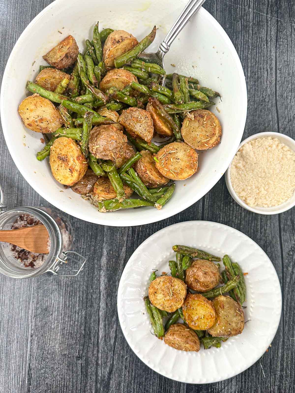aerial view of white bowl and plate with the air fryer parmesan potatoes and green beans