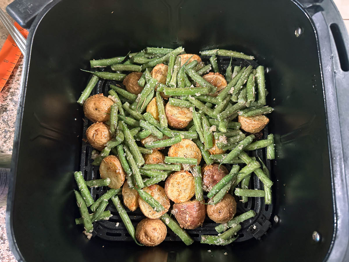 air fryer basket with semi roasted potatoes and green beans
