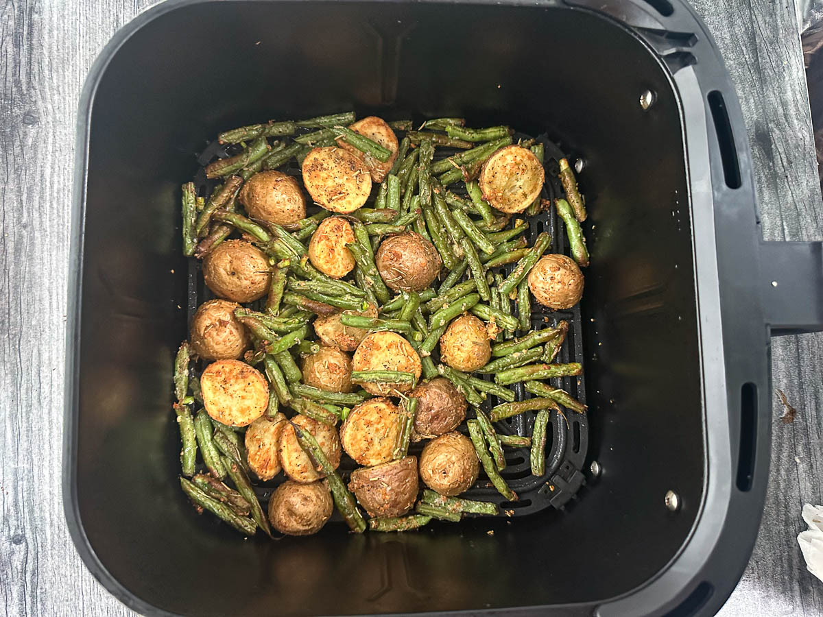 air fryer basket with finished parmesan potatoes and green beans