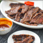 white plate and platter with grilled barbecue short ribs and text