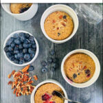 aerial view of ramekins with blueberry baked oatmeal cups and fresh blueberries and nuts and text