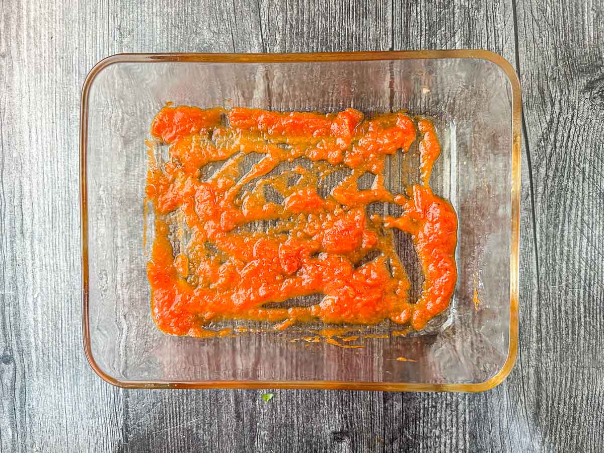 baking dish with a layer of sauce
