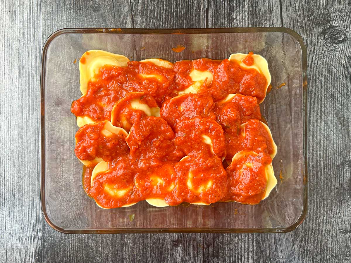 baking dish with a layer of ravioli covered in sauce