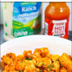 closeup of a bowl of buffalo cauliflower and bottles in the background with text
