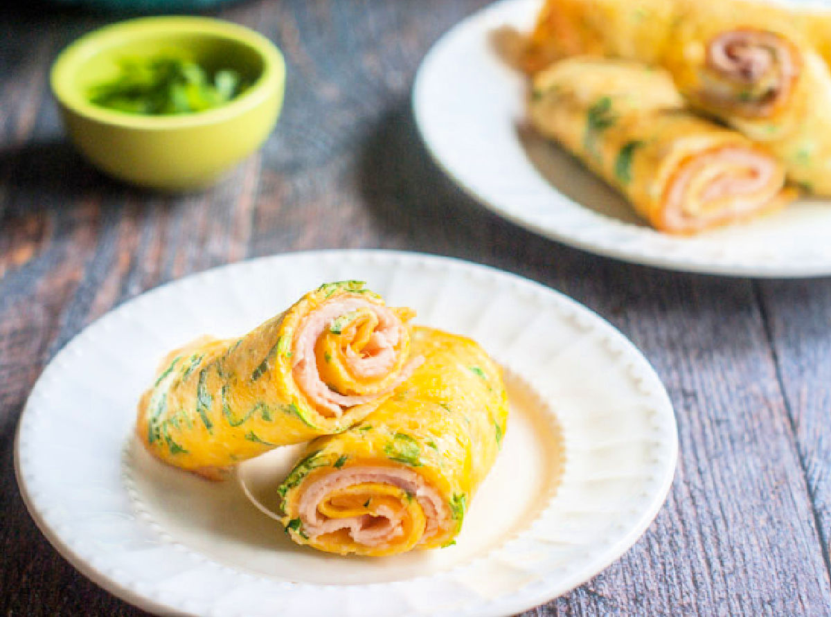 white plates with turkey egg roll ups and green bowl with herbs