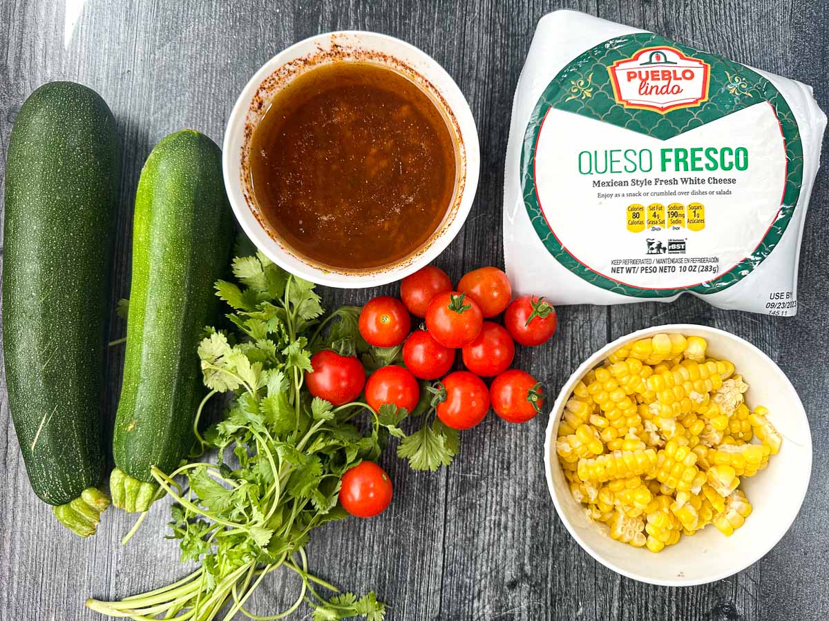recipe ingredients - fresh cilantro, zucchini, corn, cherry tomatoes, queso cheese and dressing