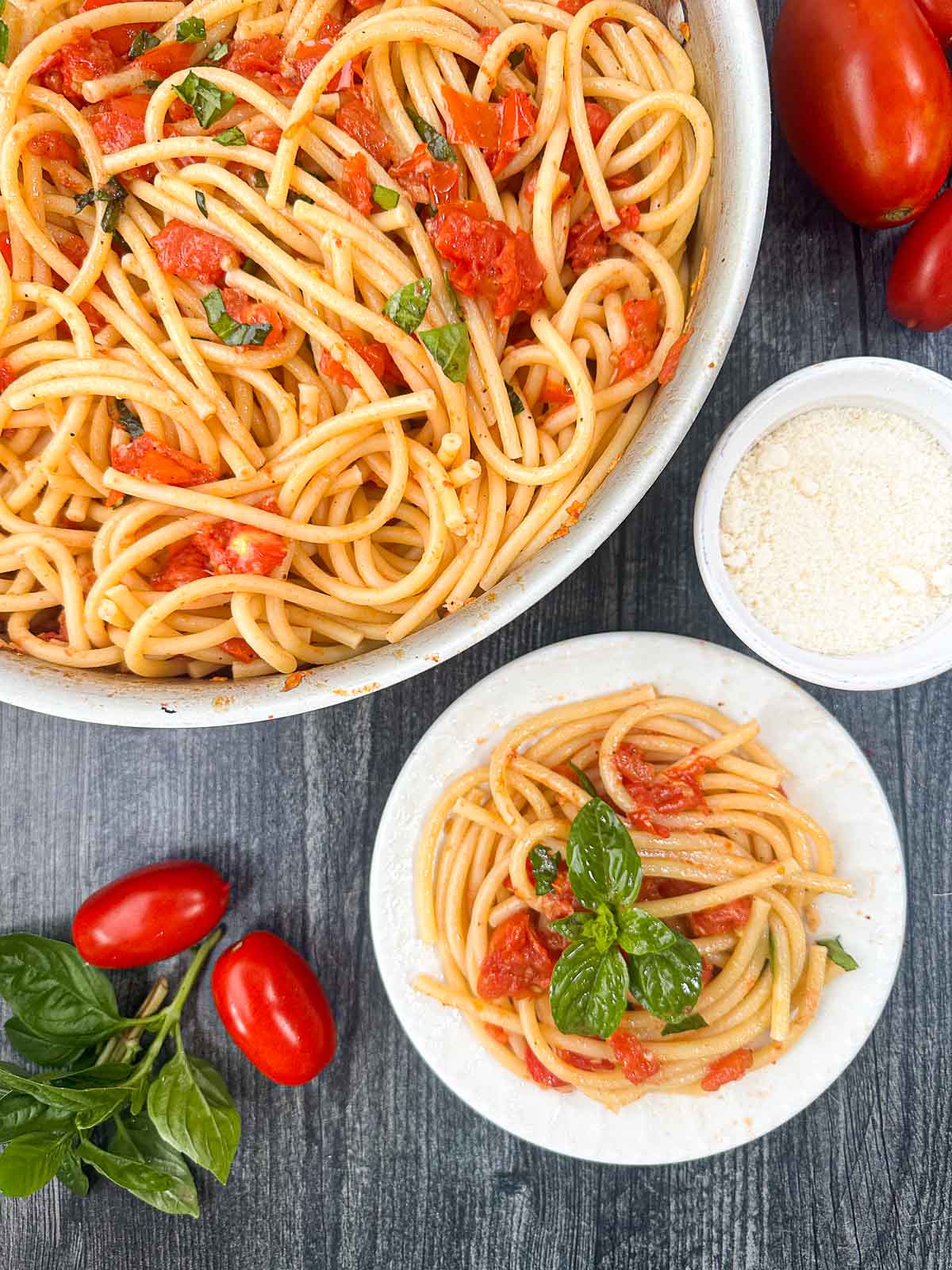 aerial view of a white bowl and plate with fresh tomato pasta with basil and garlic
