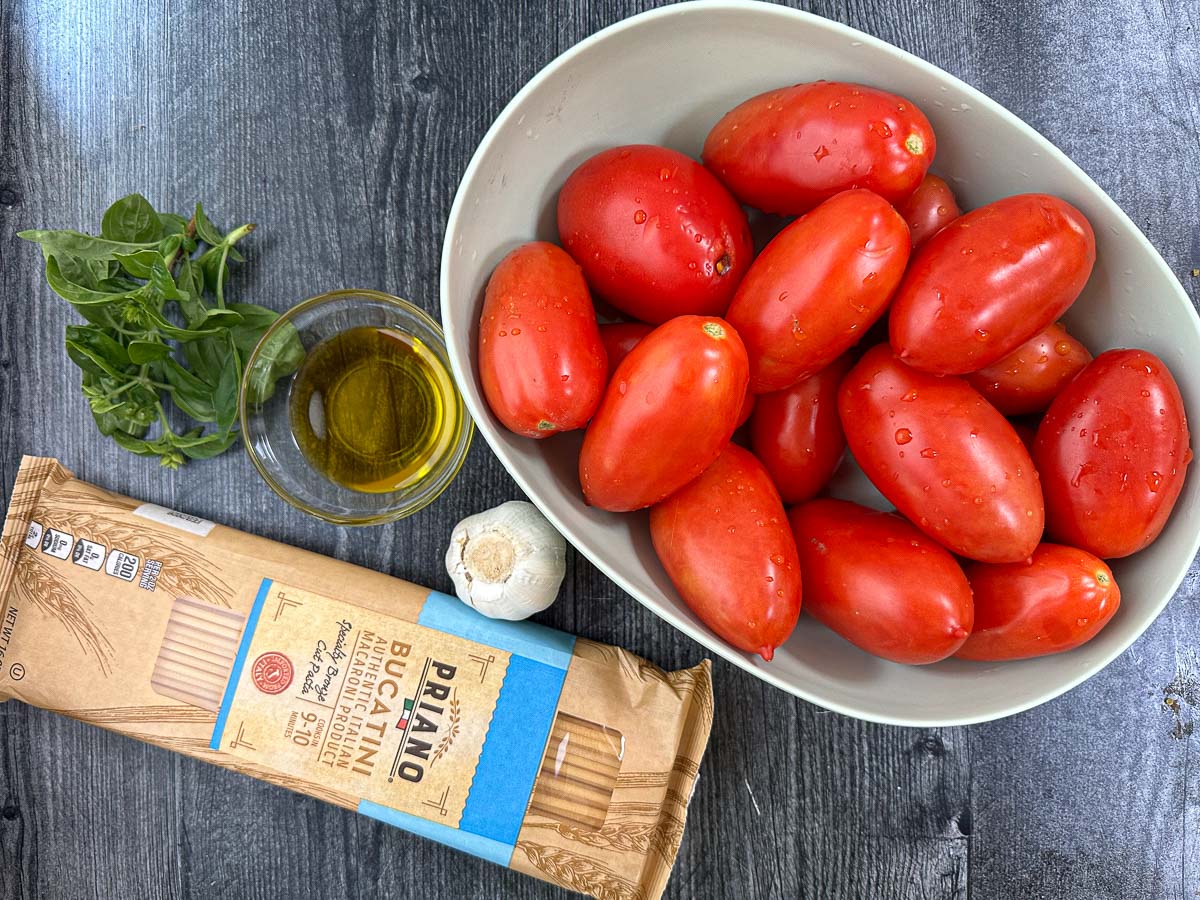 recipe ingredients - plum tomatoes, bucatini, basil leaves, olive oil and fresh garlic