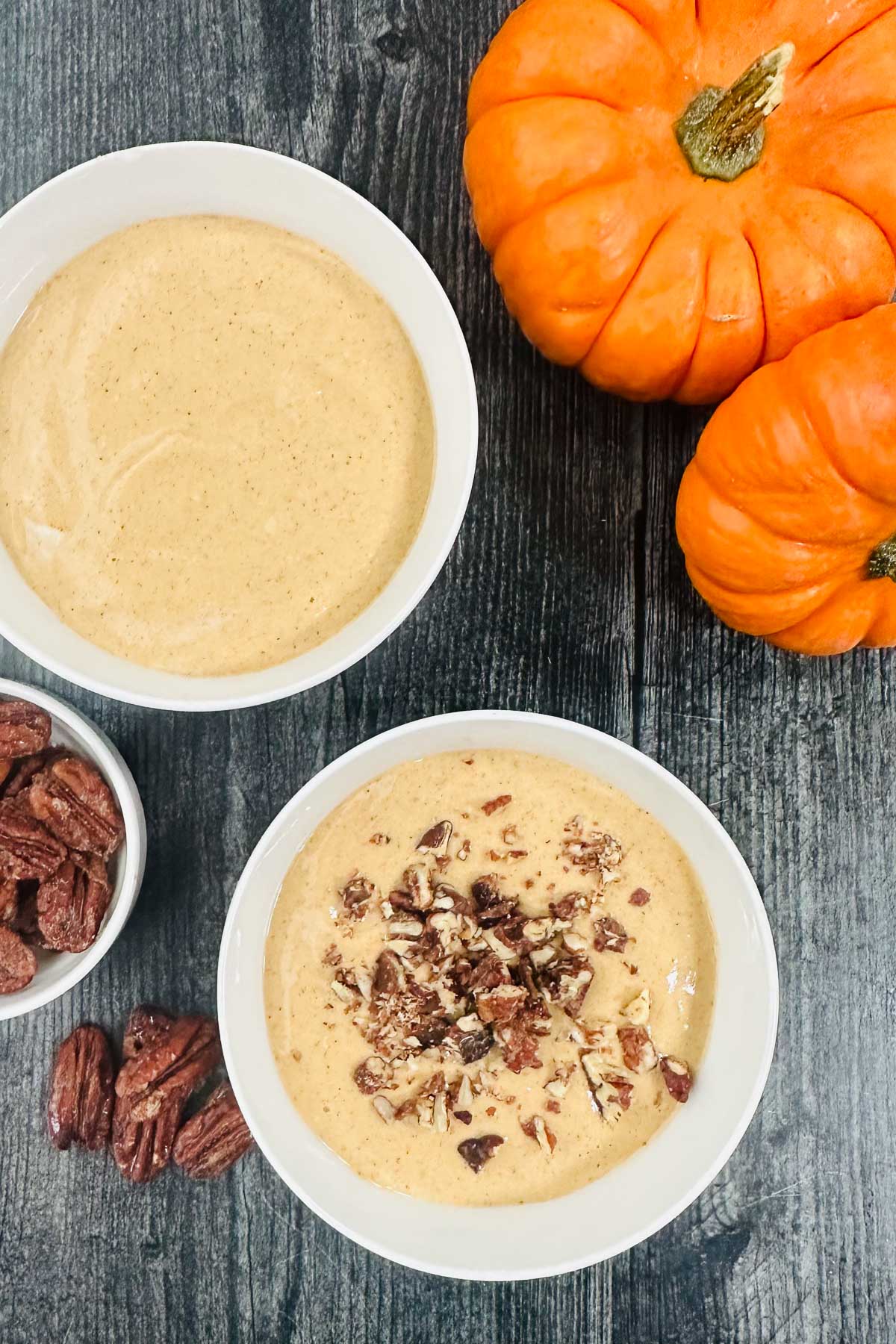 aerial view of 2 bowls of whipped cottage with nuts and little pumpkins