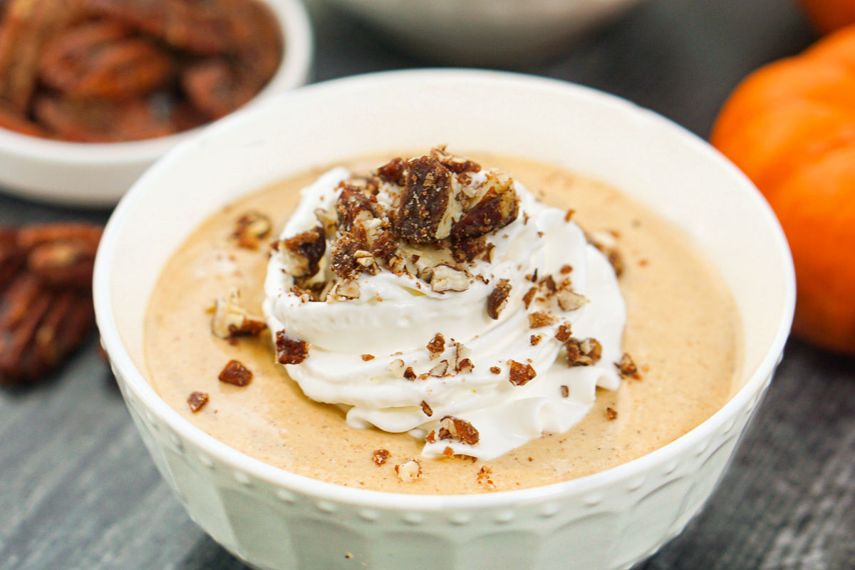 white bowl with whipped pumpkin dessert with whipped cream and nuts