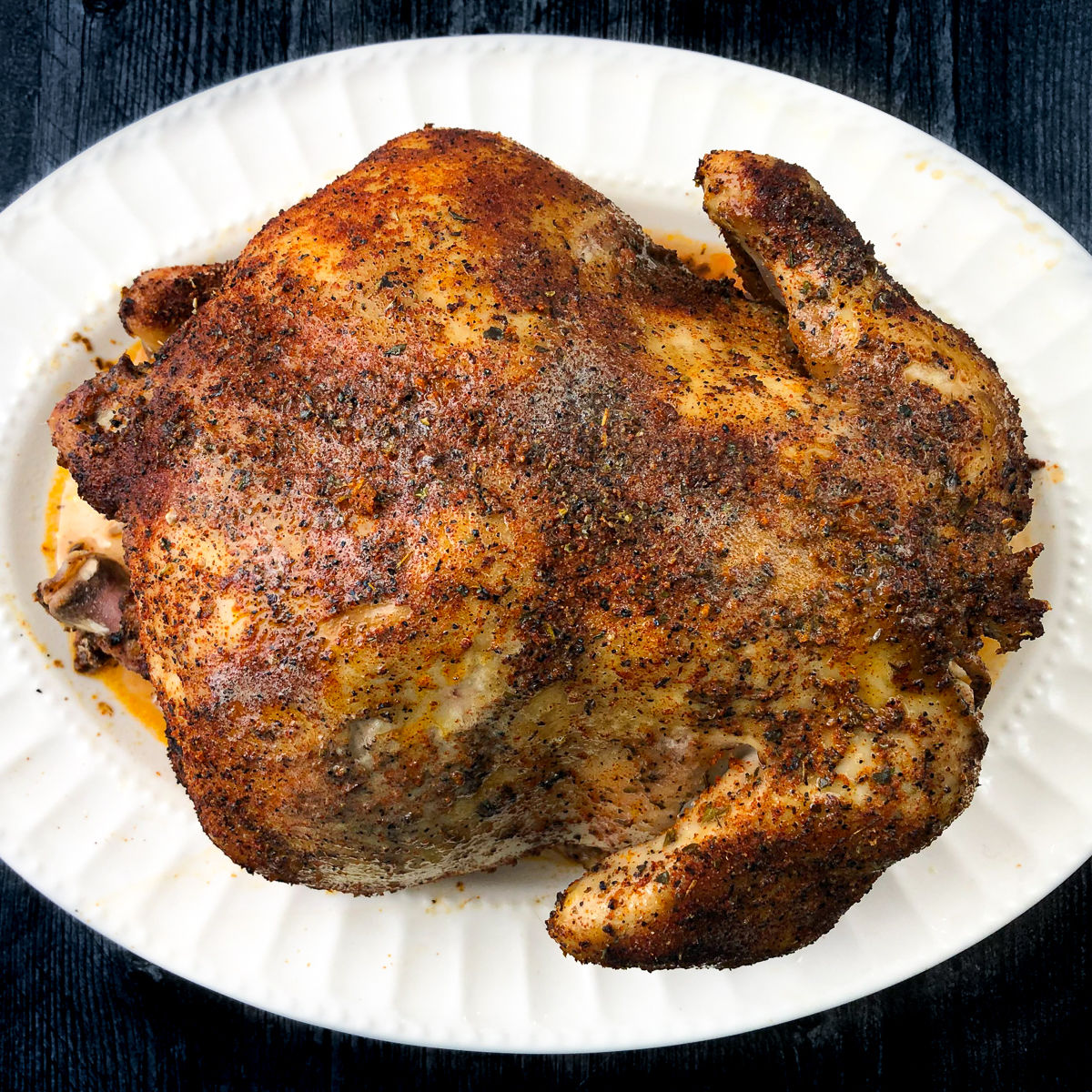 White platter with whole roasted chicken made in the slow cooker.