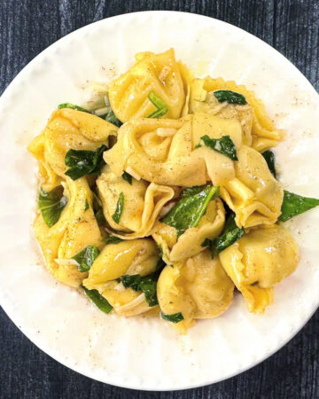 white plate with pasta with brown butter and spinach
