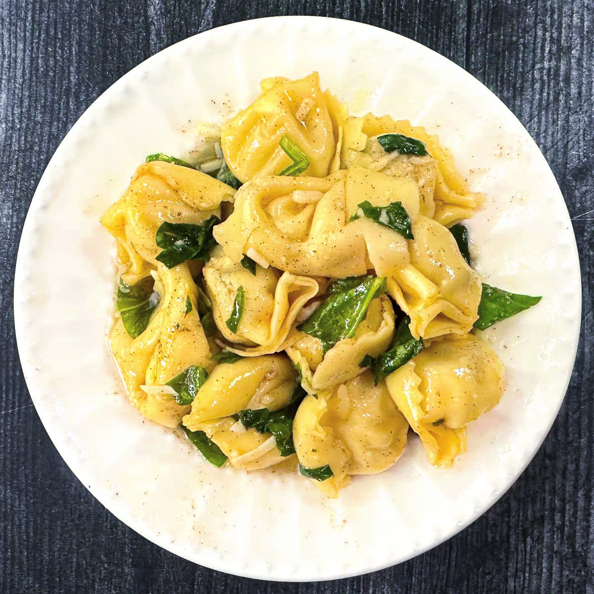 white plate with pasta with brown butter and spinach