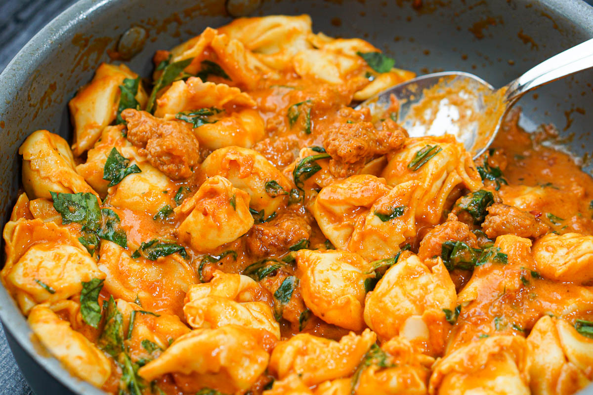 closeup of a pan of creamy vodka sauce on tortellini and sausage