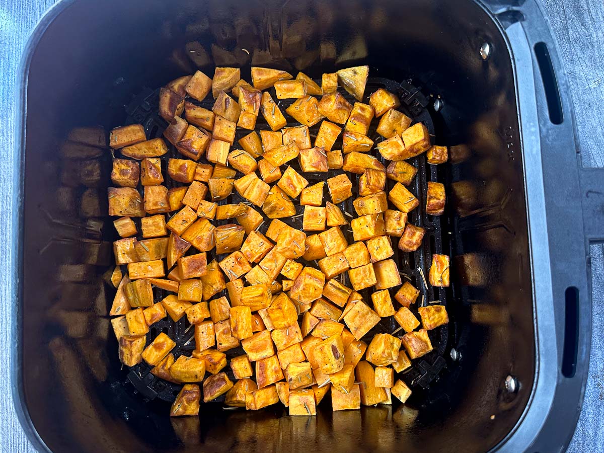 air fryer basket with roasted rosemary diced sweet potatoes