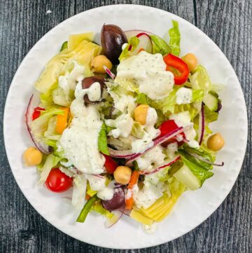 white plate with salad and creamy feta dressing