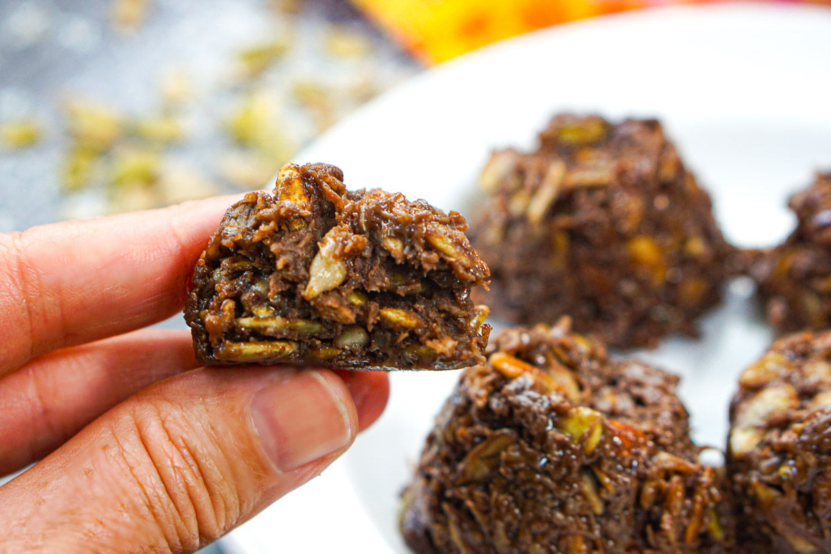 fingers holding low carb no bake seeds and chocolate cookie