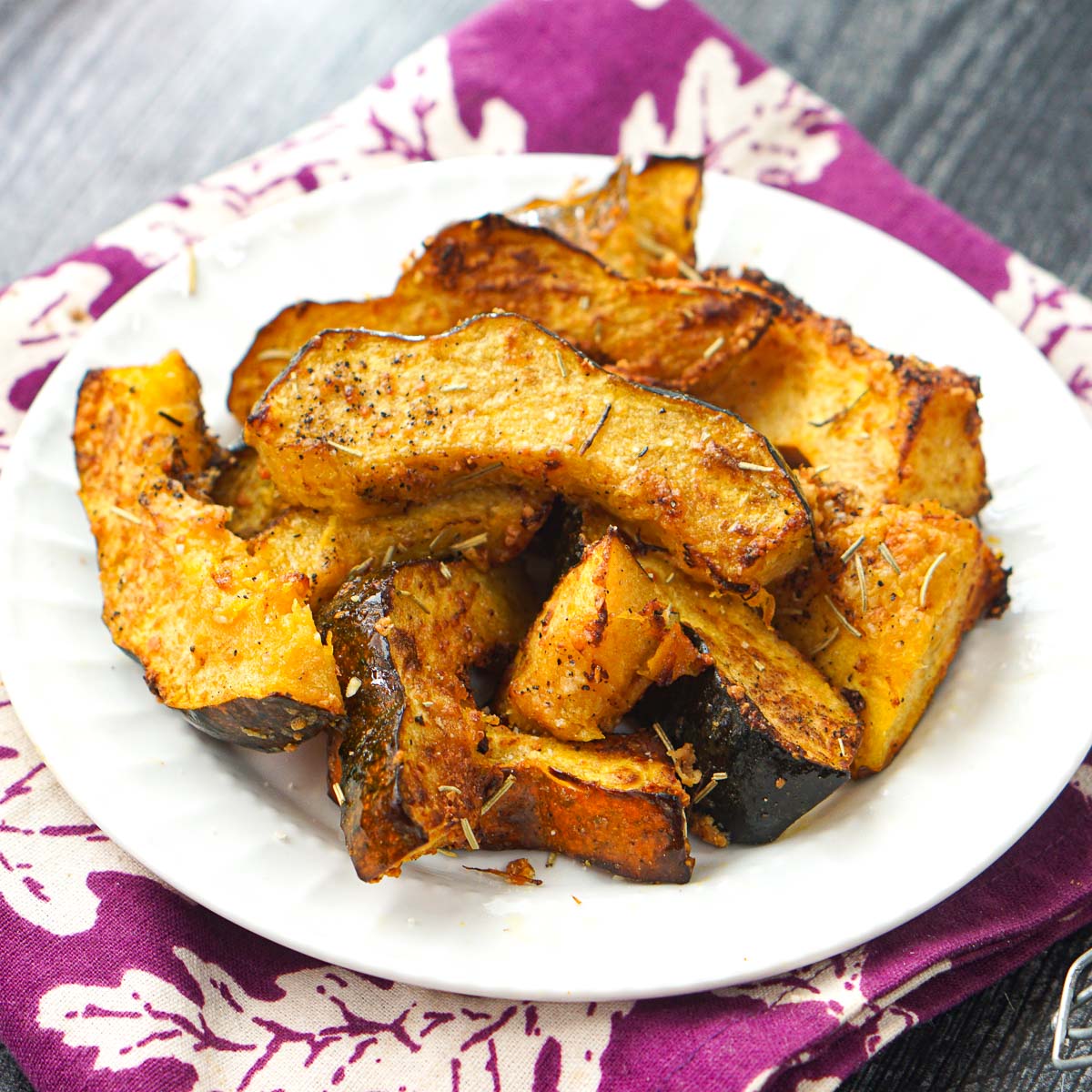 air fryer acorn squash fries on white plate and purple towel beneath