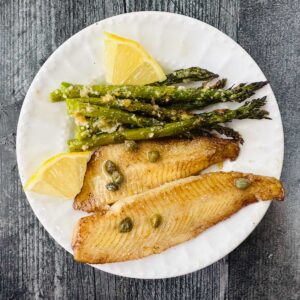 white plate with asparagus, lemons and low carb flounder piccata