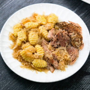 white plate with a serving pork sauerkraut and gnocchi