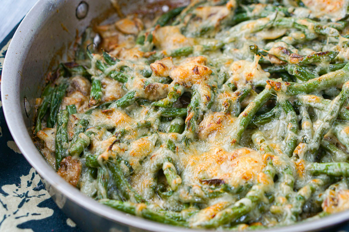 closeup of finished pan with creamy green beans and mushrooms topped with melted cheese