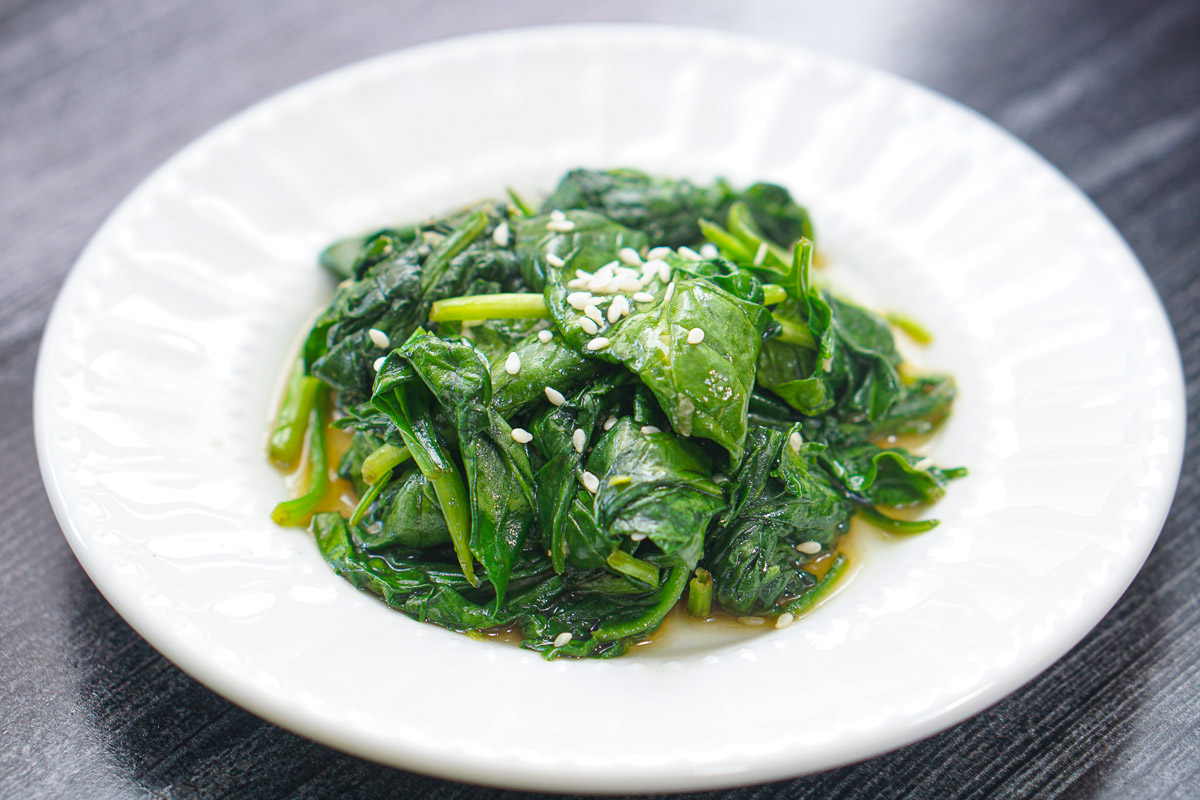 white plate with Asian spinach stir fry with sesame seeds