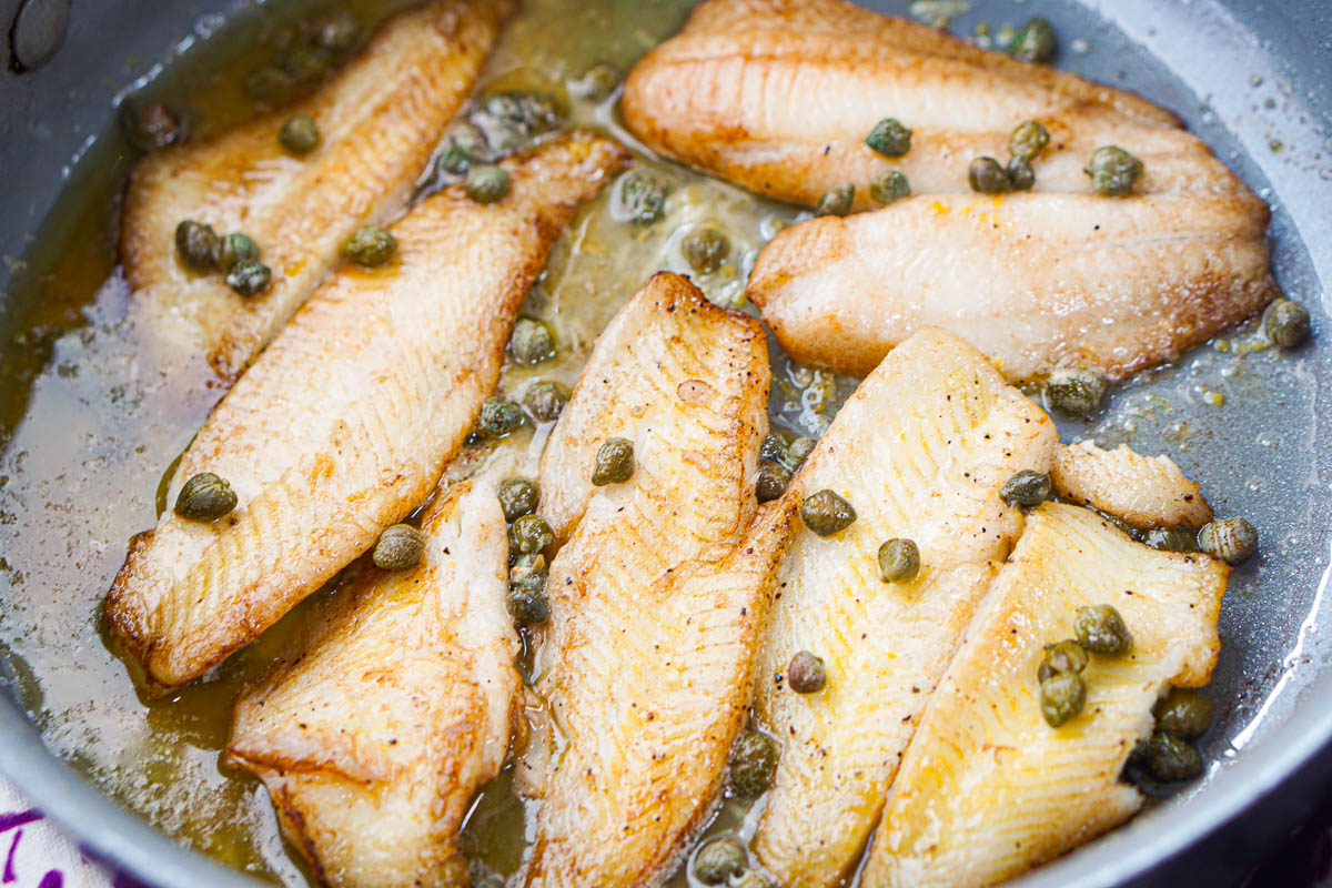 closeup of a pan of flounder with butter and capers