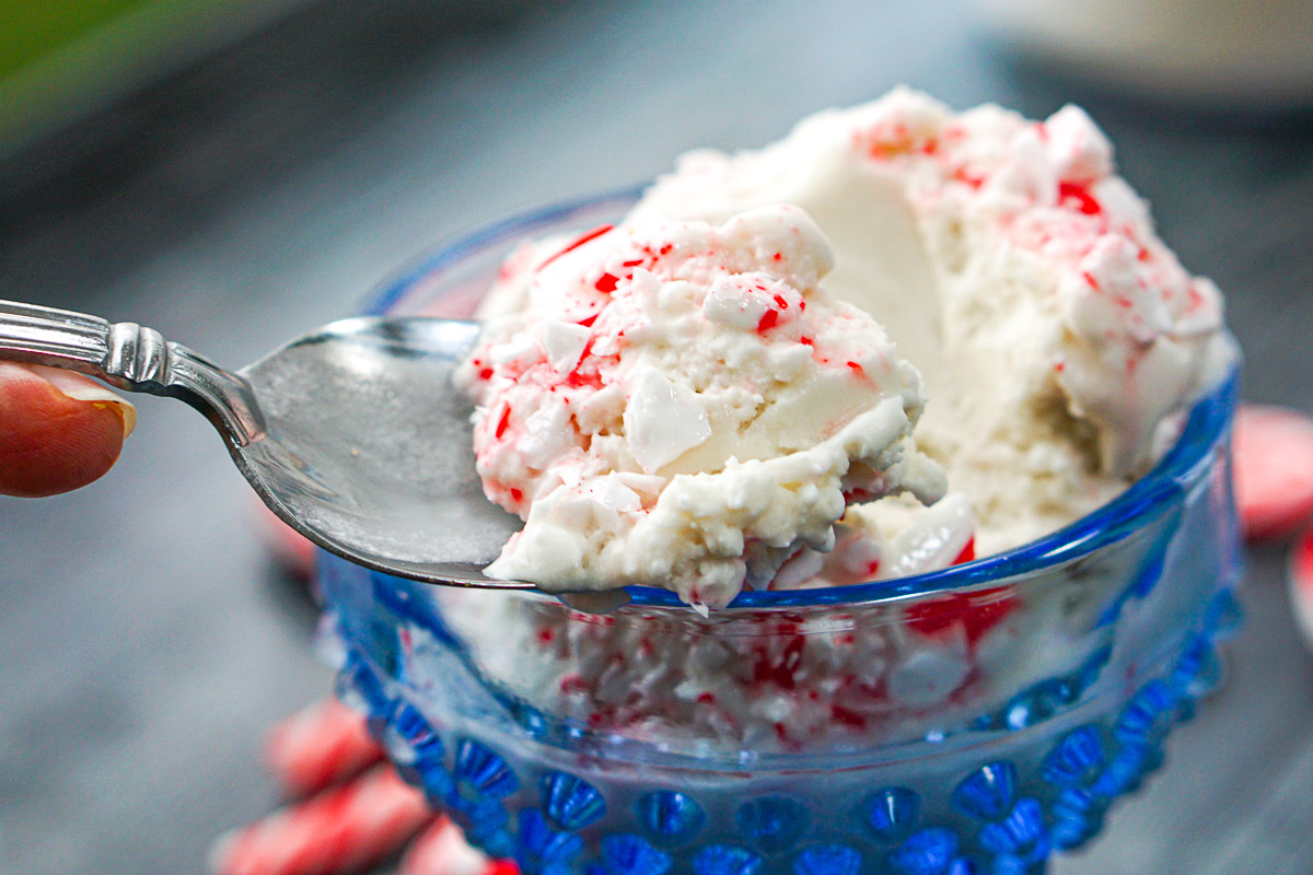 closeup of a spoonful of keto candy cane ice cream in blue glass dish